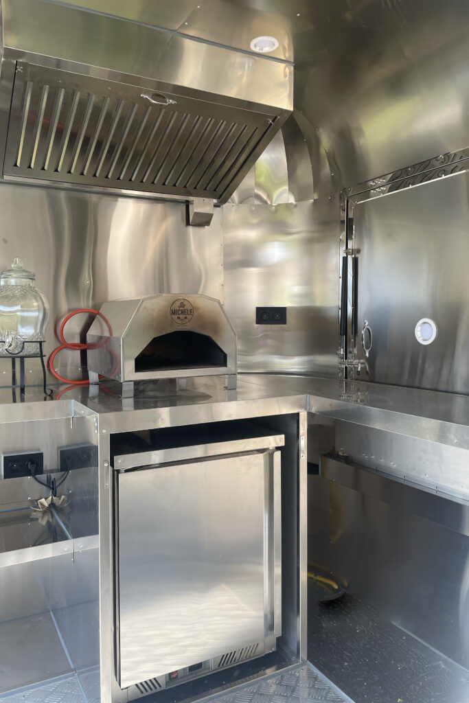 Innenraum mit Dunstabzug und Pizzaofen und Kühlschrank